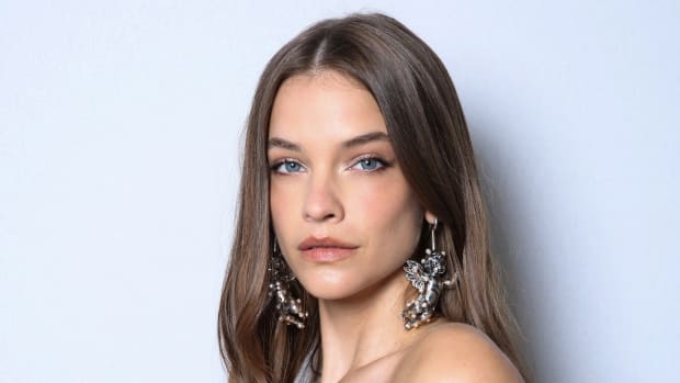 Barbara Palvin wears oversized silver cherub earrings and poses for the camera in front of a white background.