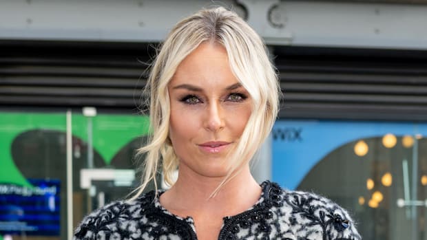 Lindsey Vonn poses in a black and white jacket and a messy up-do and smiles for the camera.