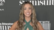 Katie Austin smiles at the camera wearing a green halter dress and her dark blonde hair in a beach wave.