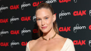 Bar Refaeli smiles at the camera wearing a cream square-neck dress and a thick gold necklace.
