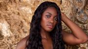 Sloane Stephens poses in front of the natural rocks with her black hair in a beach wave.