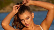 Olivia Brower poses in front of the water with her hands on her head.