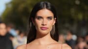 Sara Sampaio poses for the camera wearing small gold hoop earrings and her brown hair combed back behind her ears.