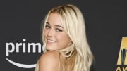 Olivia Dunne poses and smiles over her shoulder at the camera. She wears her blond hair down in a light wave.