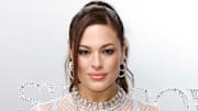 Ashley Graham poses in a dress made of Swarovski crystals and smiles for the camera.