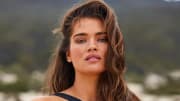Tara Lynn poses in a black swimsuit and wears her brown hair down.