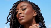 Nneka Ogwumike poses in a black one-piece and looks down at the camera.