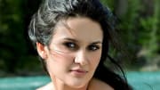Leryn Franco poses in front of a vibrant blue lake and looks intently at the camera.