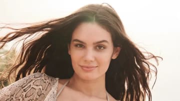 Anne de Paula poses for the camera, wearing a snakeskin-printed top and her brown hair down.