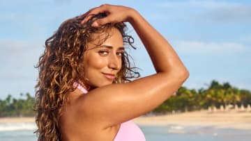 Sarafina El-Badry Nance poses in front of the ocean in a pink bikini and wet curly hair.