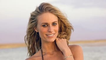 Julie Henderson poses in front of the Chilean desert and smiles at the camera in a brown string bikini.