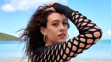 Breanna Stewart stands in front of the bright blue ocean in a black long-sleeve bathing suit with cut-outs.