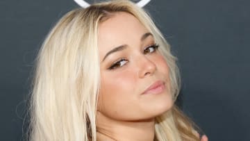 Olivia Dunne poses with her blonde hair down and looks over her shoulder at the camera.