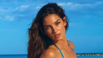 Lily Aldridge poses in front of the vibrant blue sky and ocean in a blue string bikini.