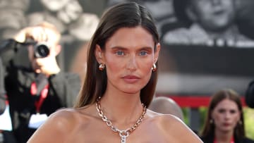 Bianca Balti poses in a gold chainlink necklace and sports a slicked back down-do.