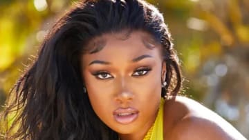 Megan Thee Stallion poses in front of a vibrant green backdrop in a bright yellow swimsuit.