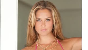 Bar Refaeli poses in a doorway in a pink bathing suit and necklace.