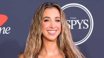 Katie Austin poses in a black dress and wears her dirty blonde hair in a beach wave.