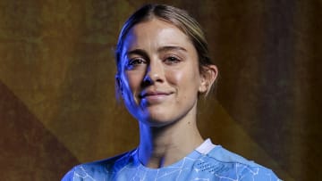 Abby Dahlkemper poses in a light blue soccer jersey and wears her dirty blonde hair in an up-do.