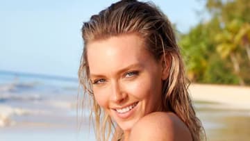 Camille Kostek poses in front of the ocean and sports wet hair.