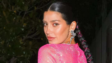 Nicole Williams English poses in a pink sparkly netted dress and looks over her shoulder at the camera.