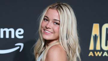 Olivia Dunne poses in a silver metallic dress and smiles over her shoulder at the camera.