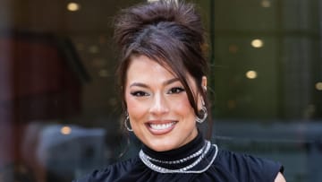 Ashley Graham poses in a black high-neck dress and diamond necklaces.