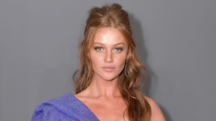 Cintia Dicker poses in a one-shoulder purple dress and wears her red hair in a half updo. Cintia Dicker poses in a one-shoulder purple dress and wears her red hair in a half updo.