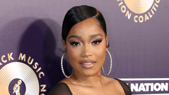 Keke Palmer poses in a black dress, oversized diamond hoops and a slicked back updo.