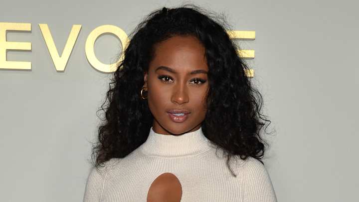 Kayla Nicole poses in a white knit dress in front of a white backdrop.