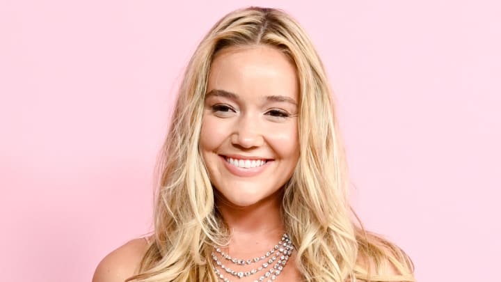 Olivia Ponton poses in a diamond necklace in front of a pink backdrop.