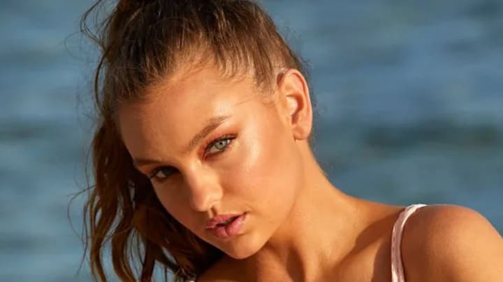 Olivia Brower poses in a white bikini before the ocean.
