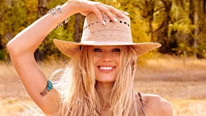 Vita Sidorkina poses with her hand resting on her straw hat and smiles for the camera. Vita Sidorkina poses with her hand resting on her straw hat and smiles for the camera.
