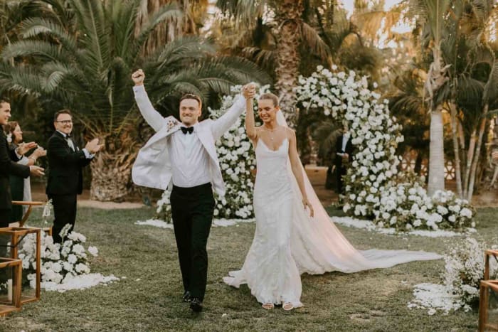 A triumphant walk down the aisle. The groom wears custom David August, the bride wears custom Alberta Ferretti