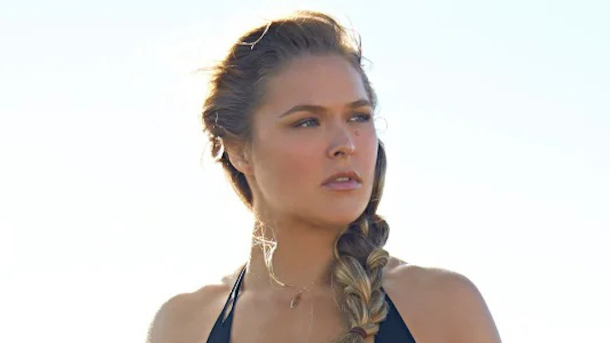 Ronda Rousey poses for the camera wearing a black halter neck bathing suit and with her hair braided.