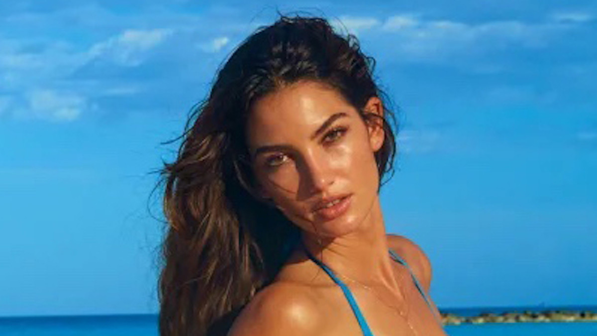 Lily Aldridge poses in front of the vibrant blue sky and ocean in a blue string bikini.