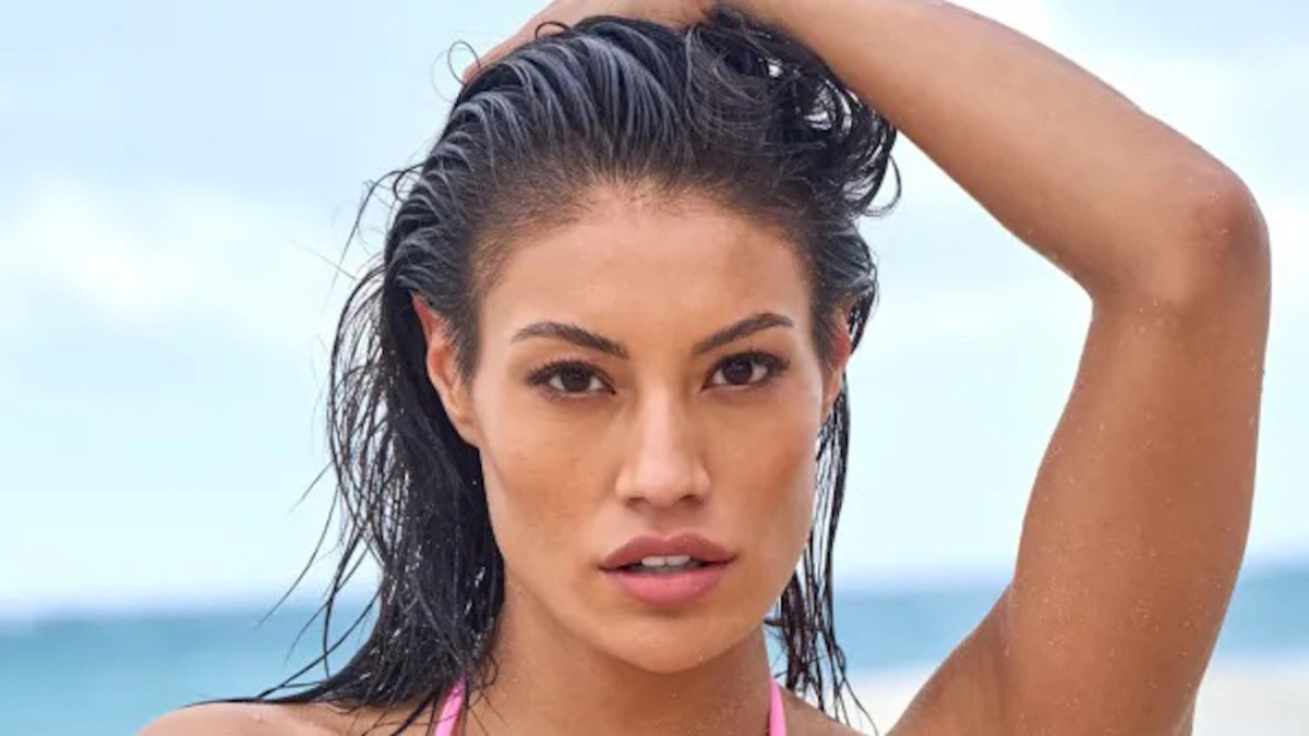 Ashley Callingbull poses in front of the ocean with her hand on her head.