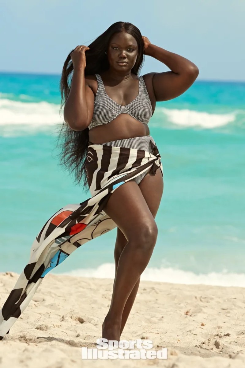 Nyma Tang stands on the beach in a black and white checkered bikini and a silk sarong.