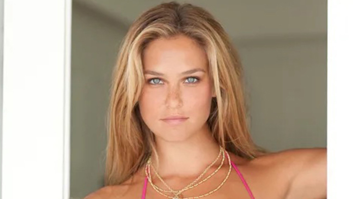 Bar Refaeli poses in a doorway in a pink bathing suit and necklace.