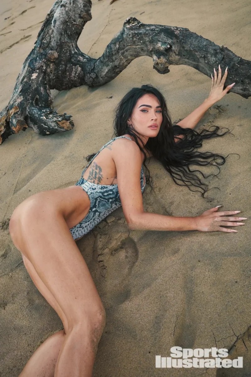 Megan Fox lays on the sand in a high-cut snakeskin one-piece.