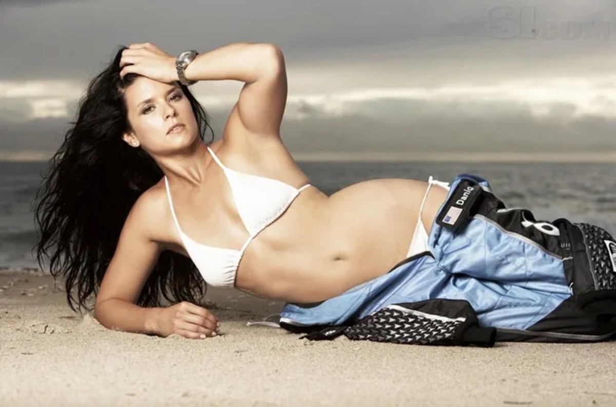 Danica Patrick lays on the sand in a white bikini and her half-zipped race car driving suit.