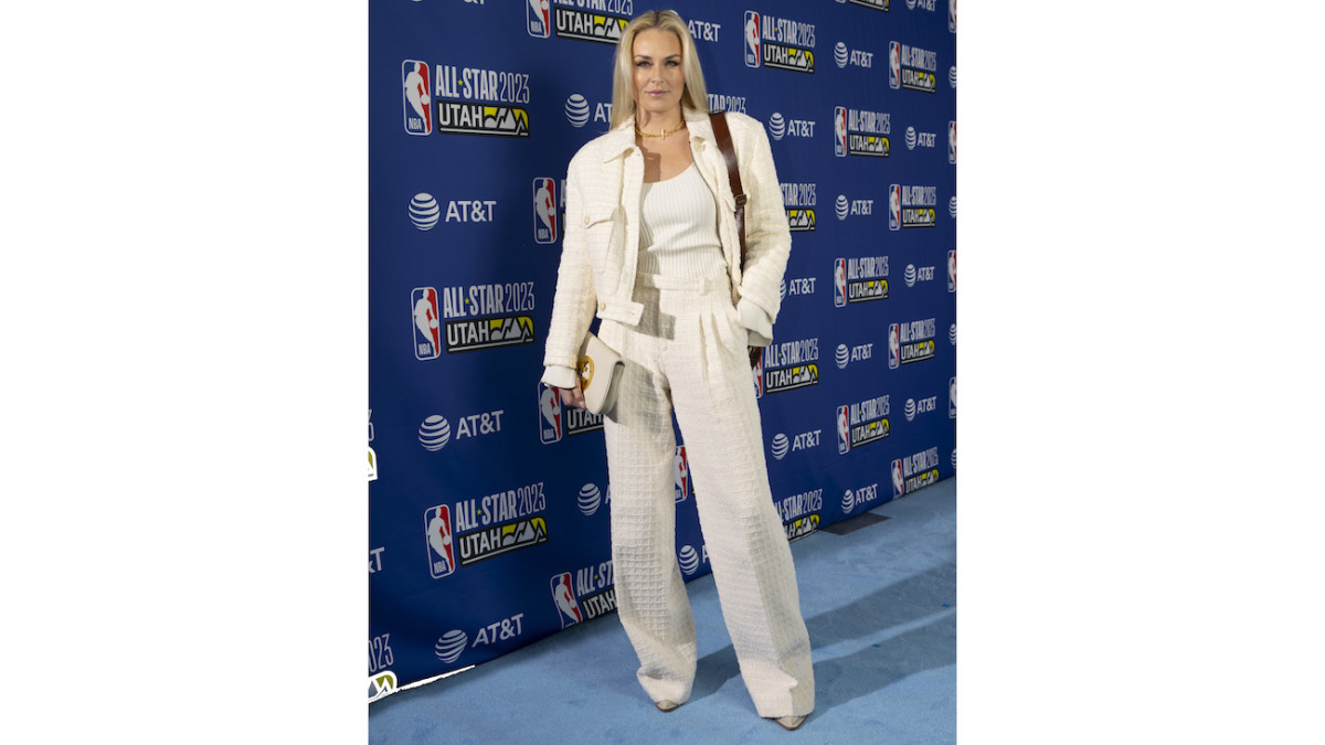 Lindsey Vonn poses in an all-white outfit on a blue carpet.