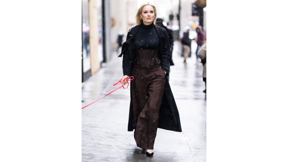 Lindsey Vonn walks down the sidewalk in a full chocolate brown set and overcoat.