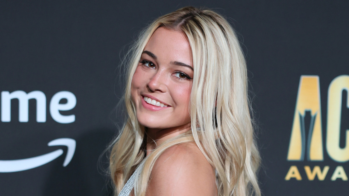 Olivia Dunne poses in a silver metallic dress and smiles over her shoulder at the camera.