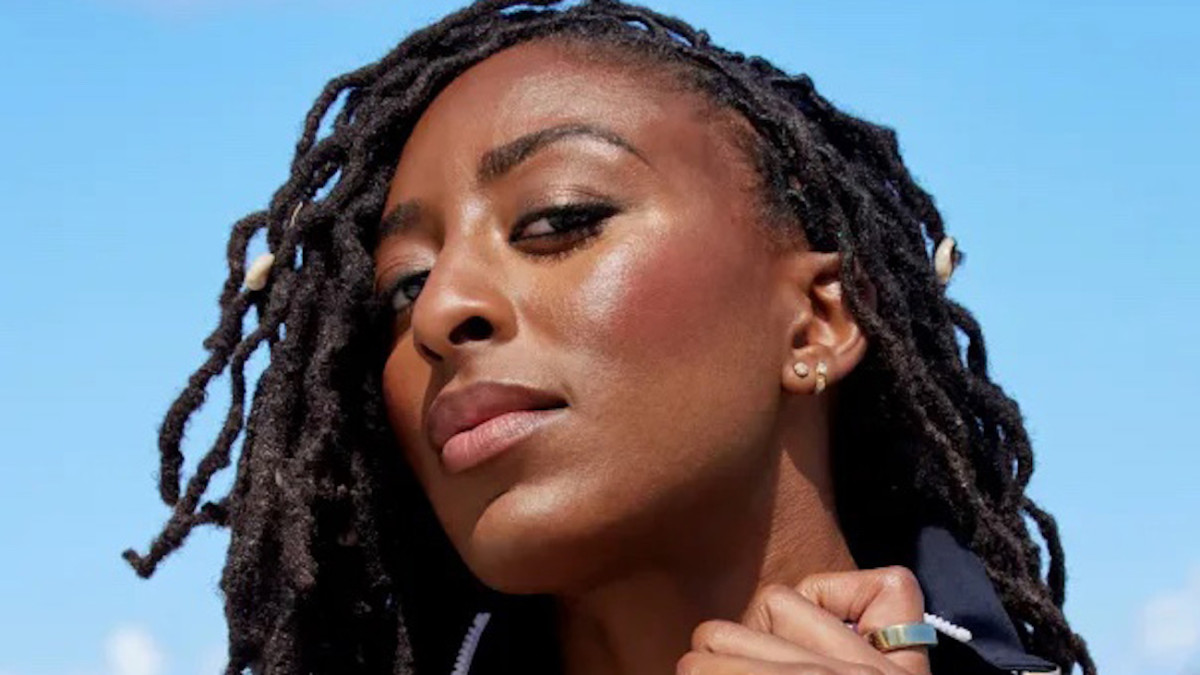 Nneka Ogwumike poses in a black one-piece and looks down at the camera.