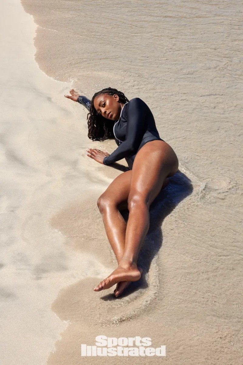 Nneka Ogwumike lays on the and in a black one-piece.