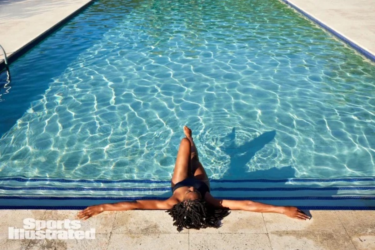 Nneka Ogwumike sits in a pool in a black swimsuit and leans back on the deck.