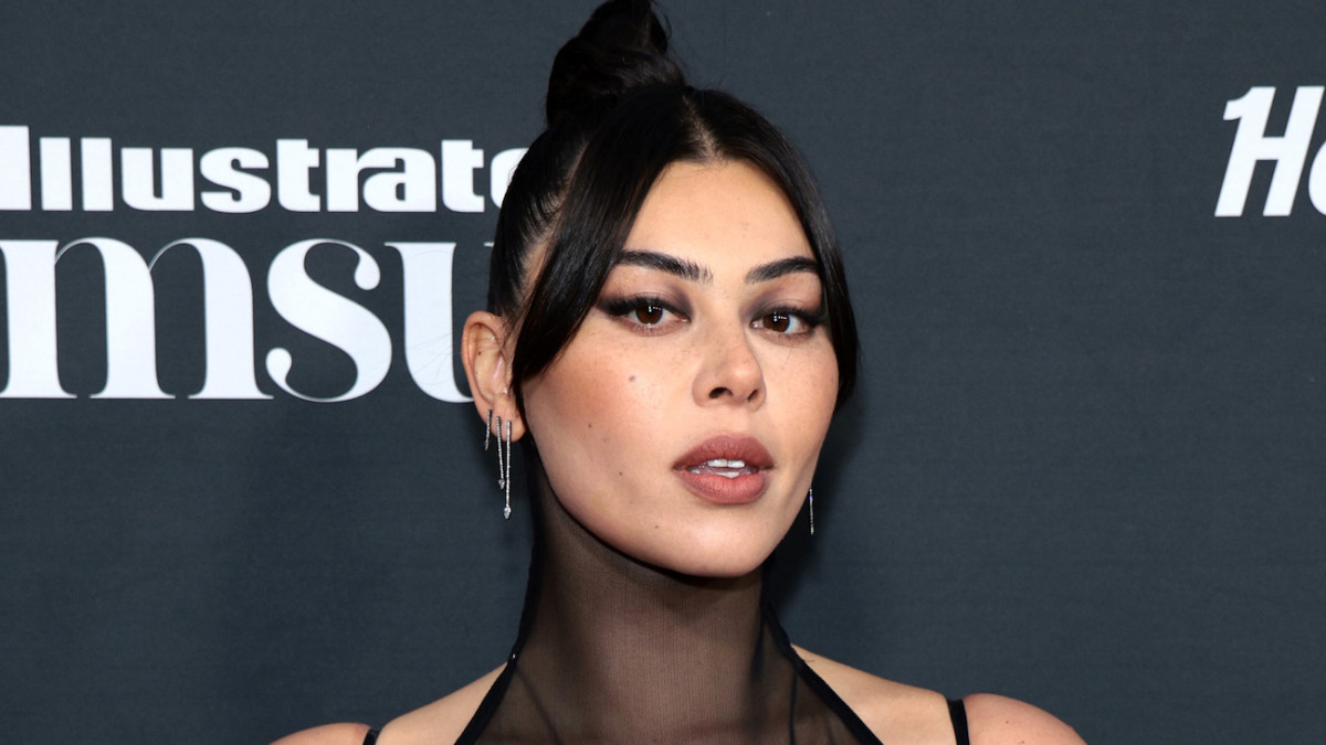 Lauren Cahn poses in a high-neck black mesh dress and a slicked-back bun.