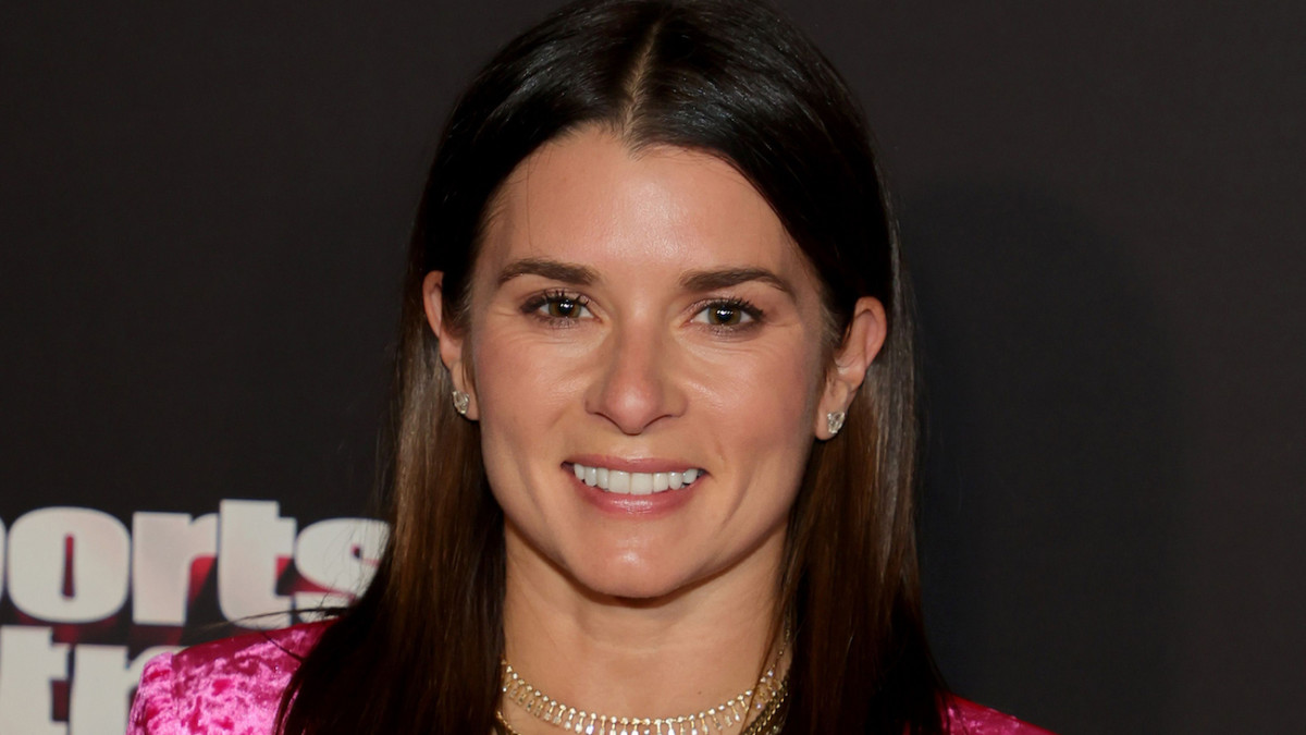 Danica Patrick poses in a pink velour blazer and smiles for the camera.